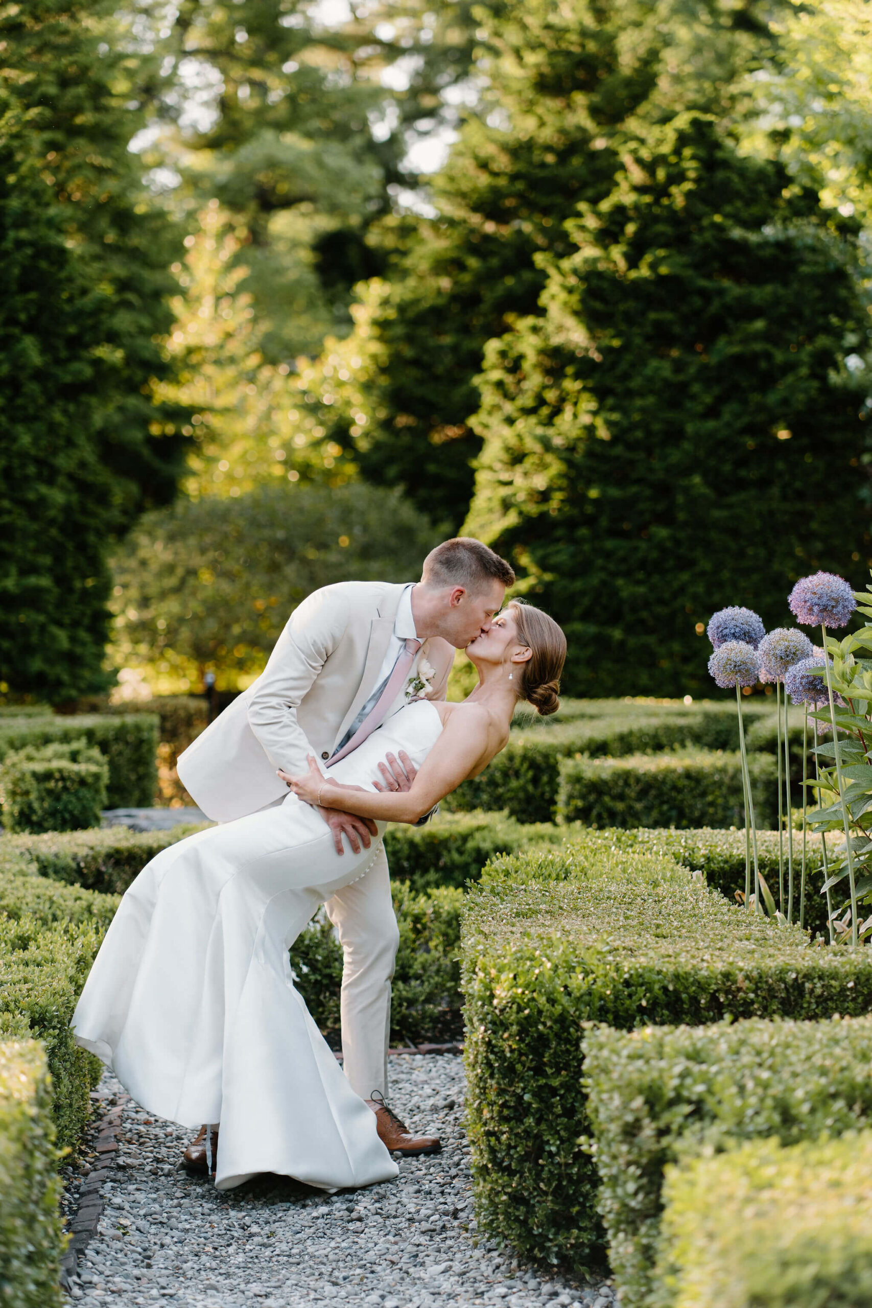 groom dipping bride in a short hedge maze garden and kissing her on a beautiful spring night