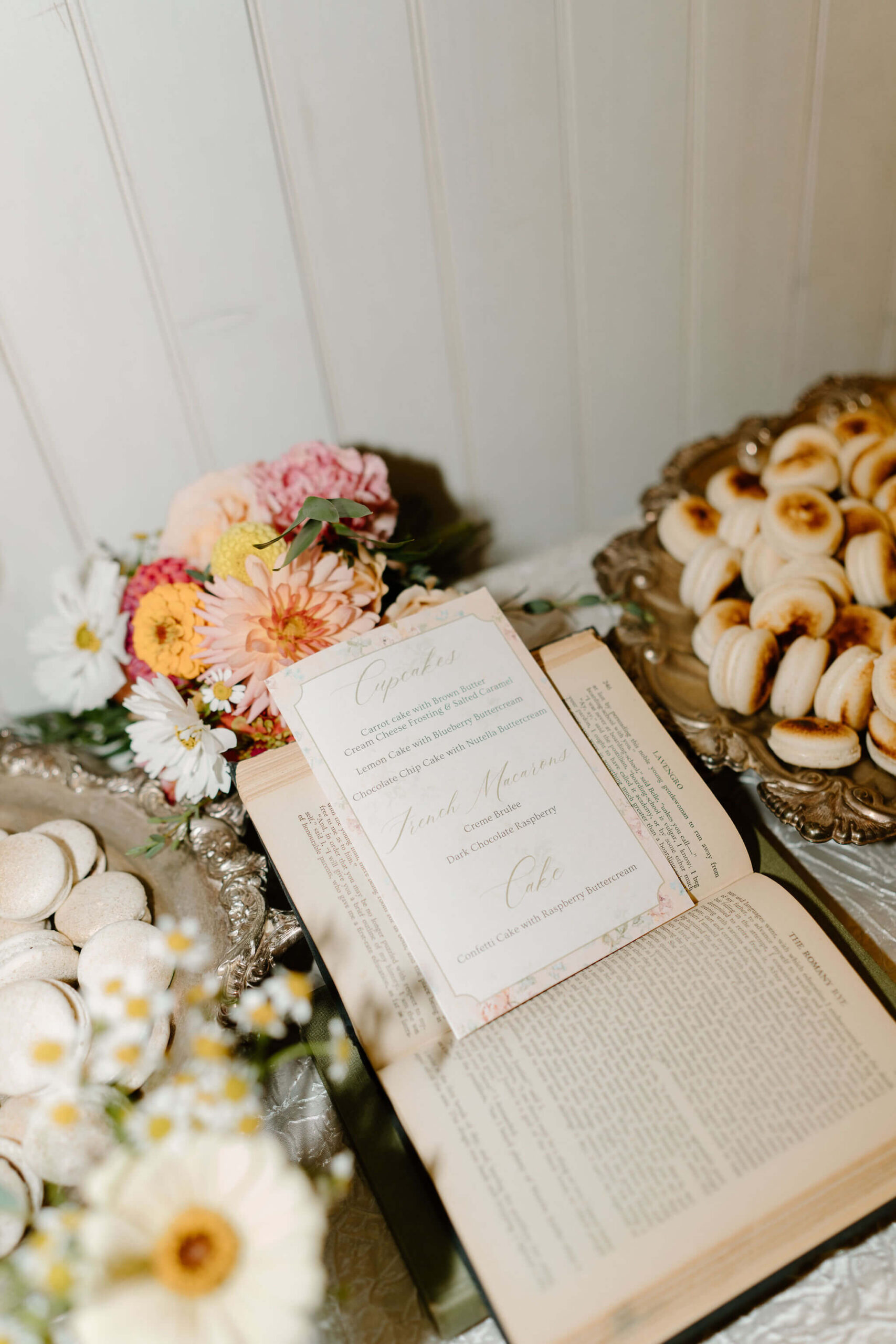 a dessert menu displayed in an old book on a dessert table at a wedding reception