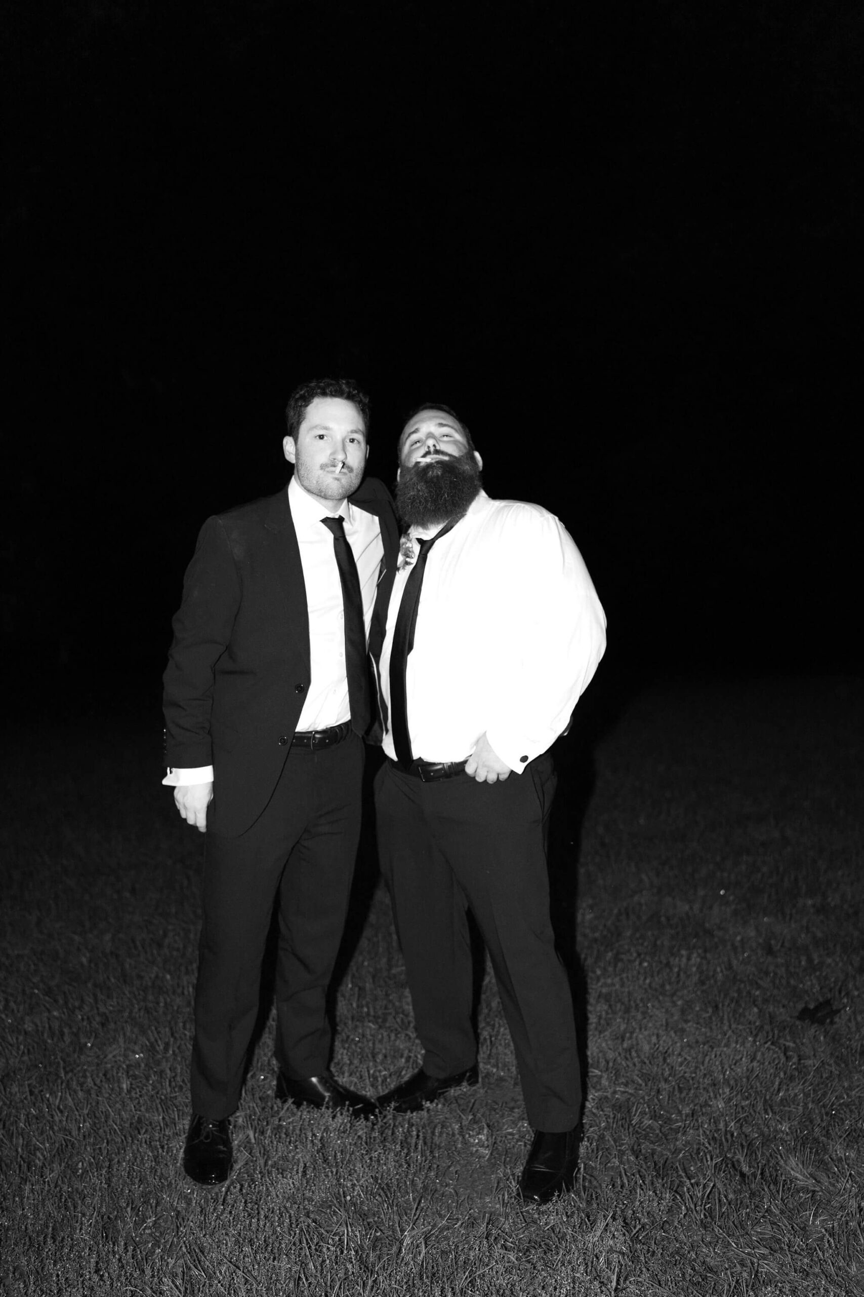 black and white image of groom and brother smoking a cigarette