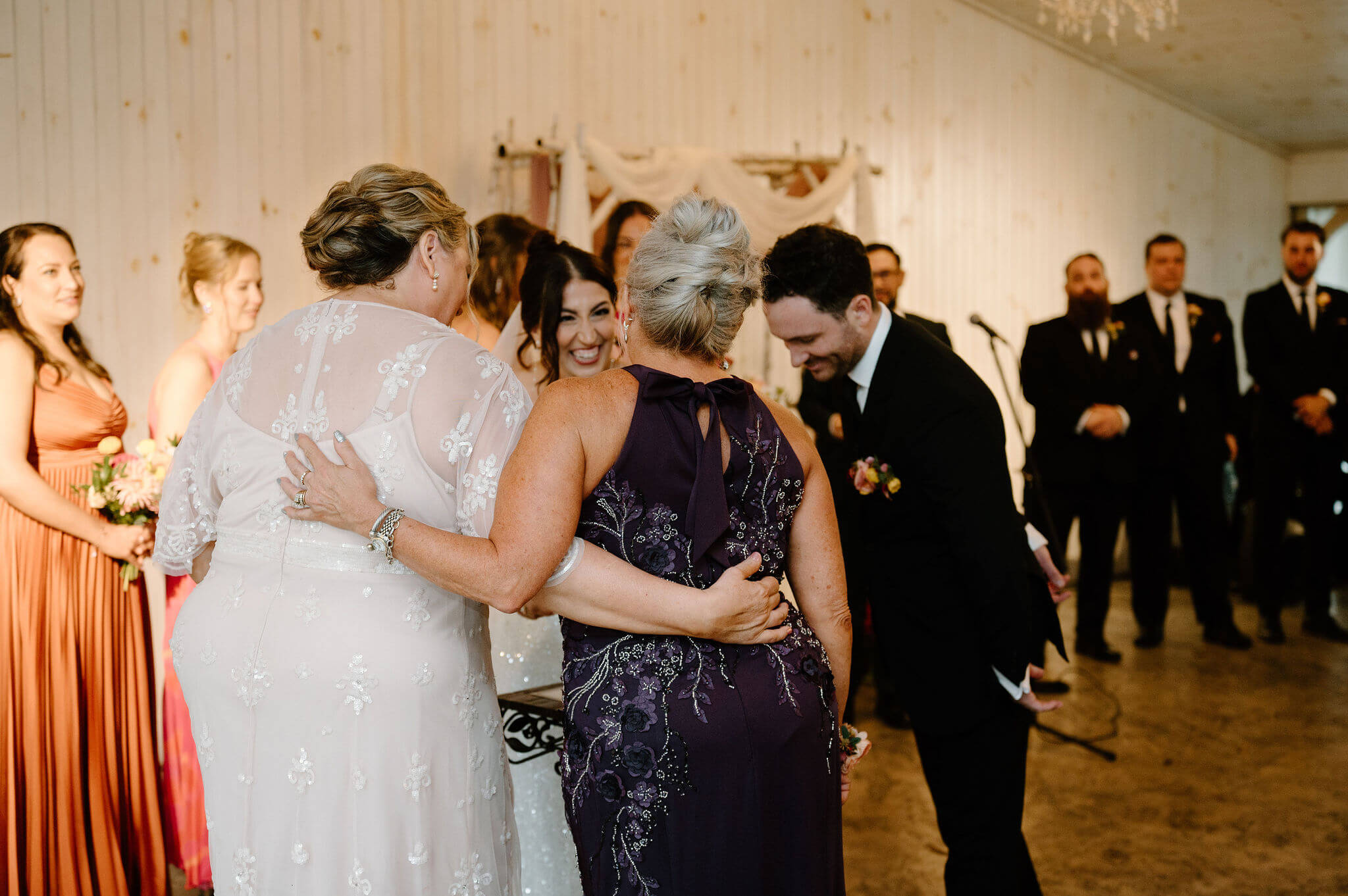 mothers of the bride and groom embracing as the bride and groom sign their marriage license