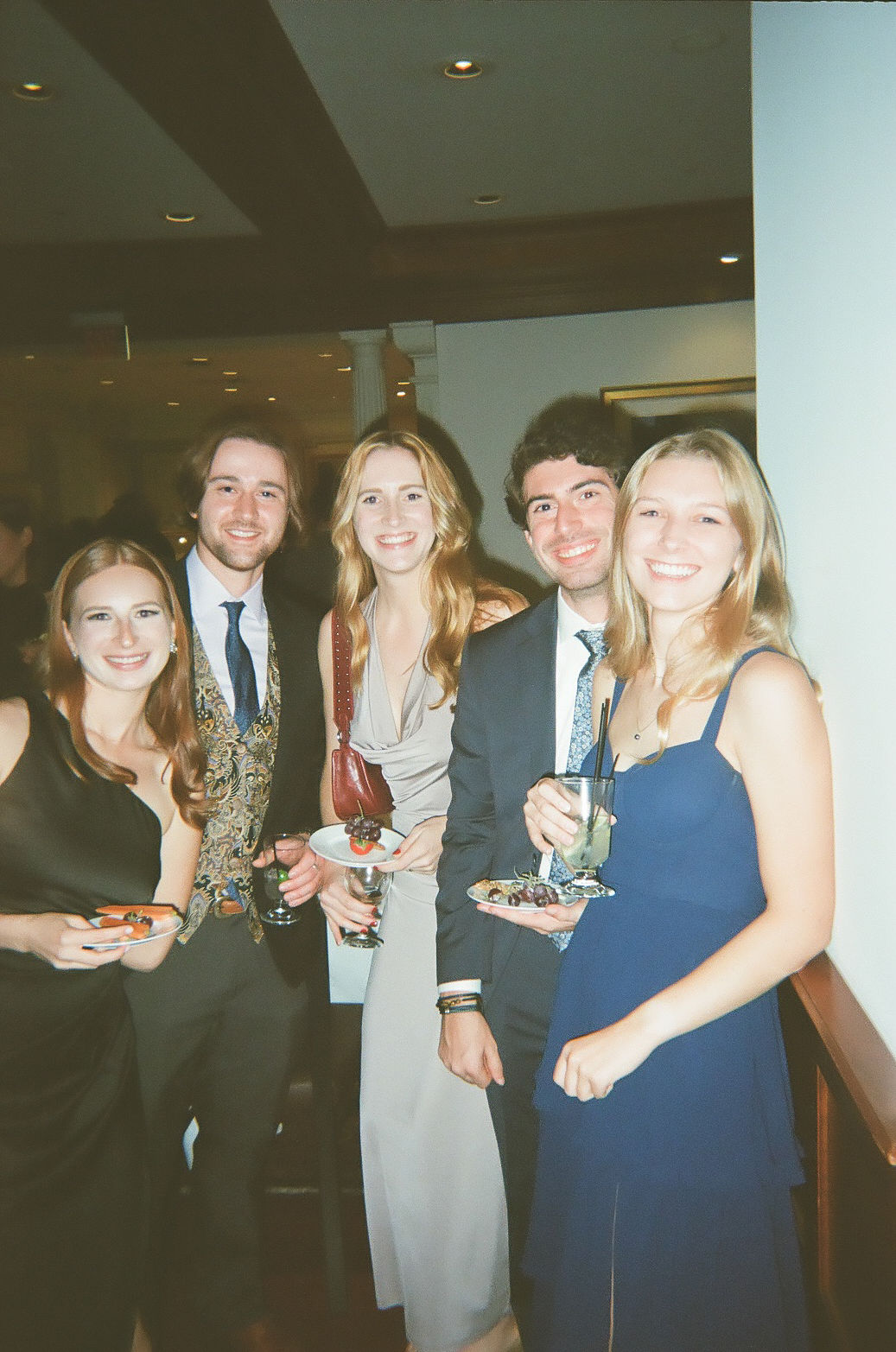 a group of friends in formalwear smiling at the camera during cocktail hour