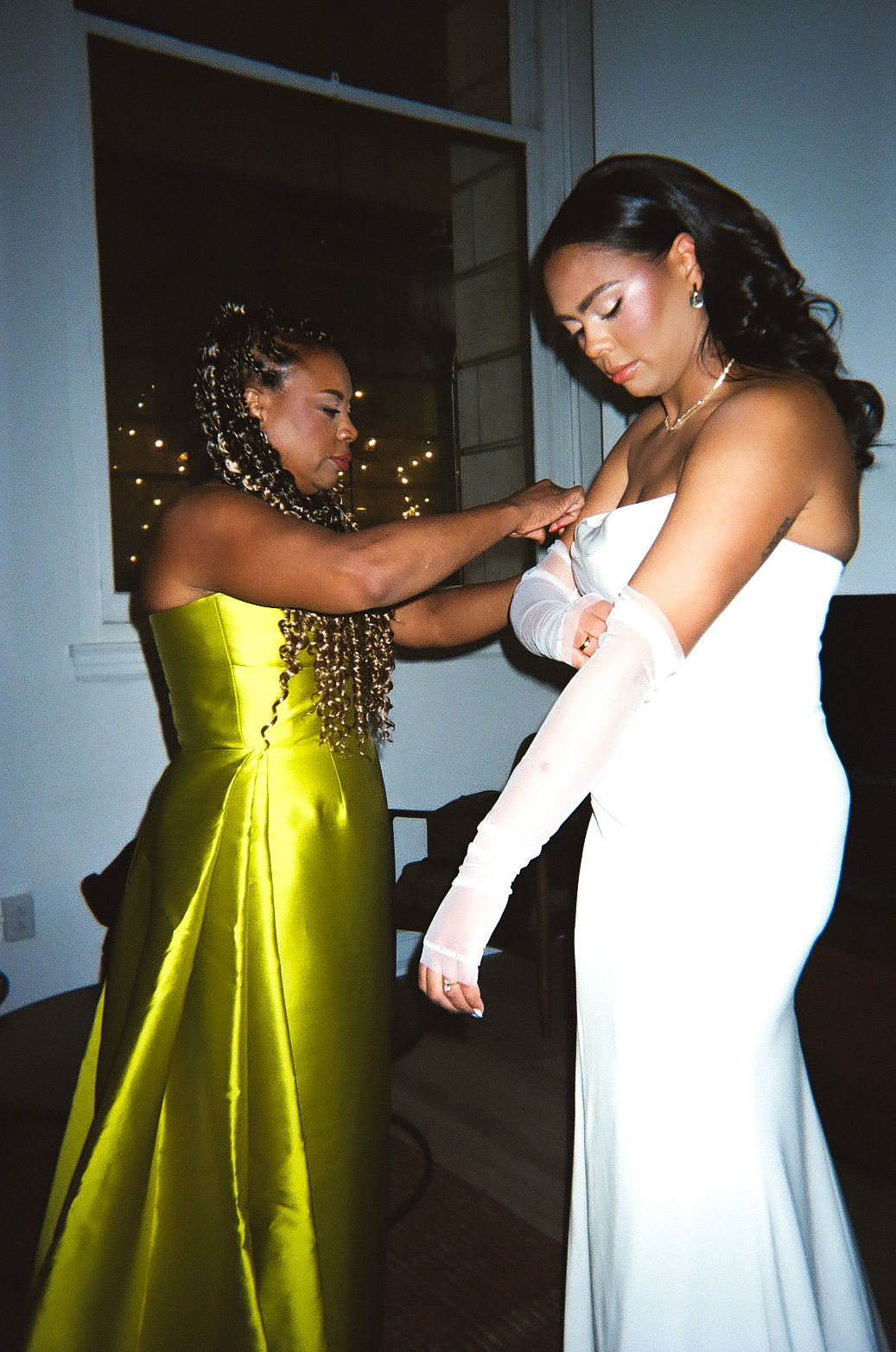 mother of the bride helping her into her wedding dress