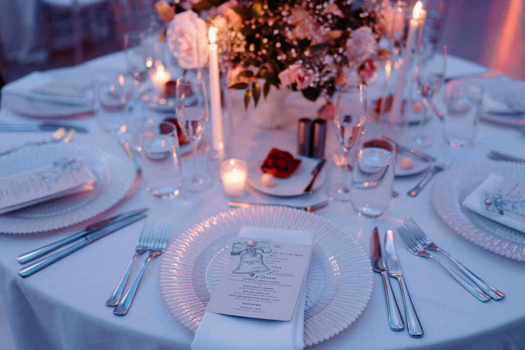 close up of menu on a plate at a wedding reception, featuring a name tag seating assignment on a cut-out of the Liberty bell