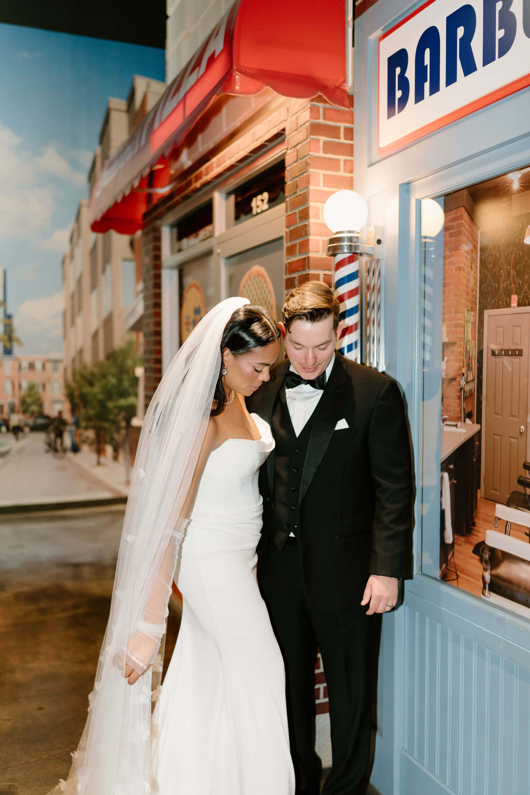 bride and groom both looking down at her dress while she situates her veil for a photo