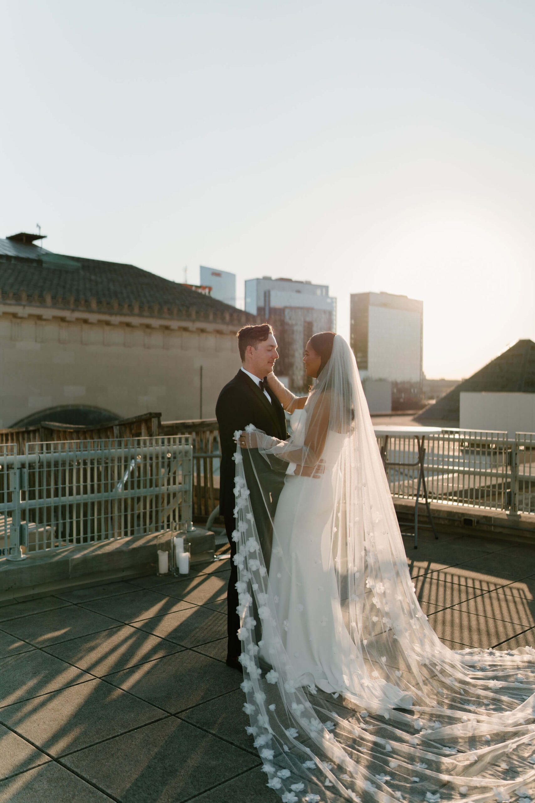 bride and groom, backlit by the sun, looking softly at each other while the bride holds a corner of her veil at their franklin institute wedding