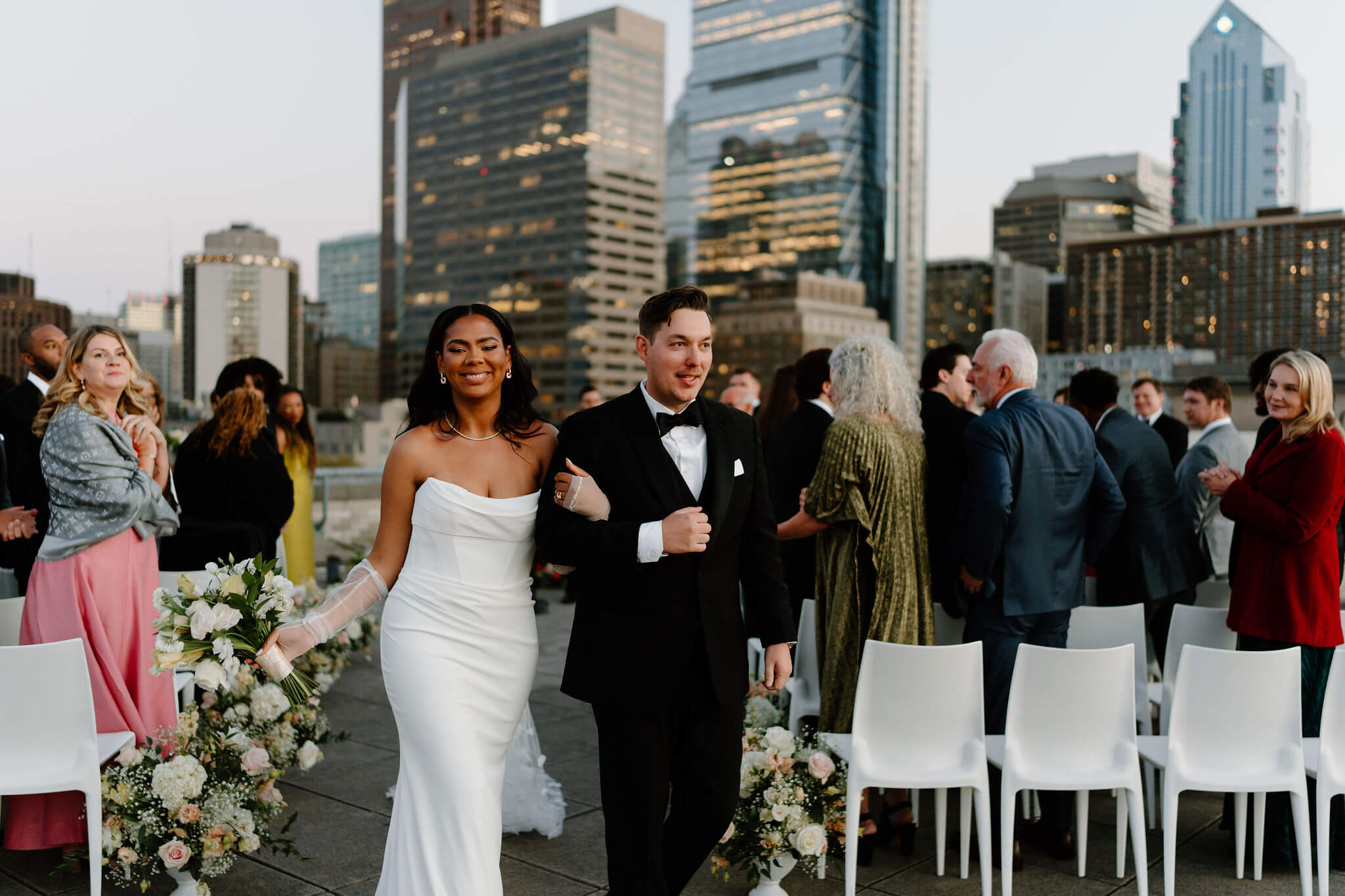 bride and groom smiling widely as they walk down the aisle after their rooftop wedding ceremony in Philadelphia, Pennsylvania