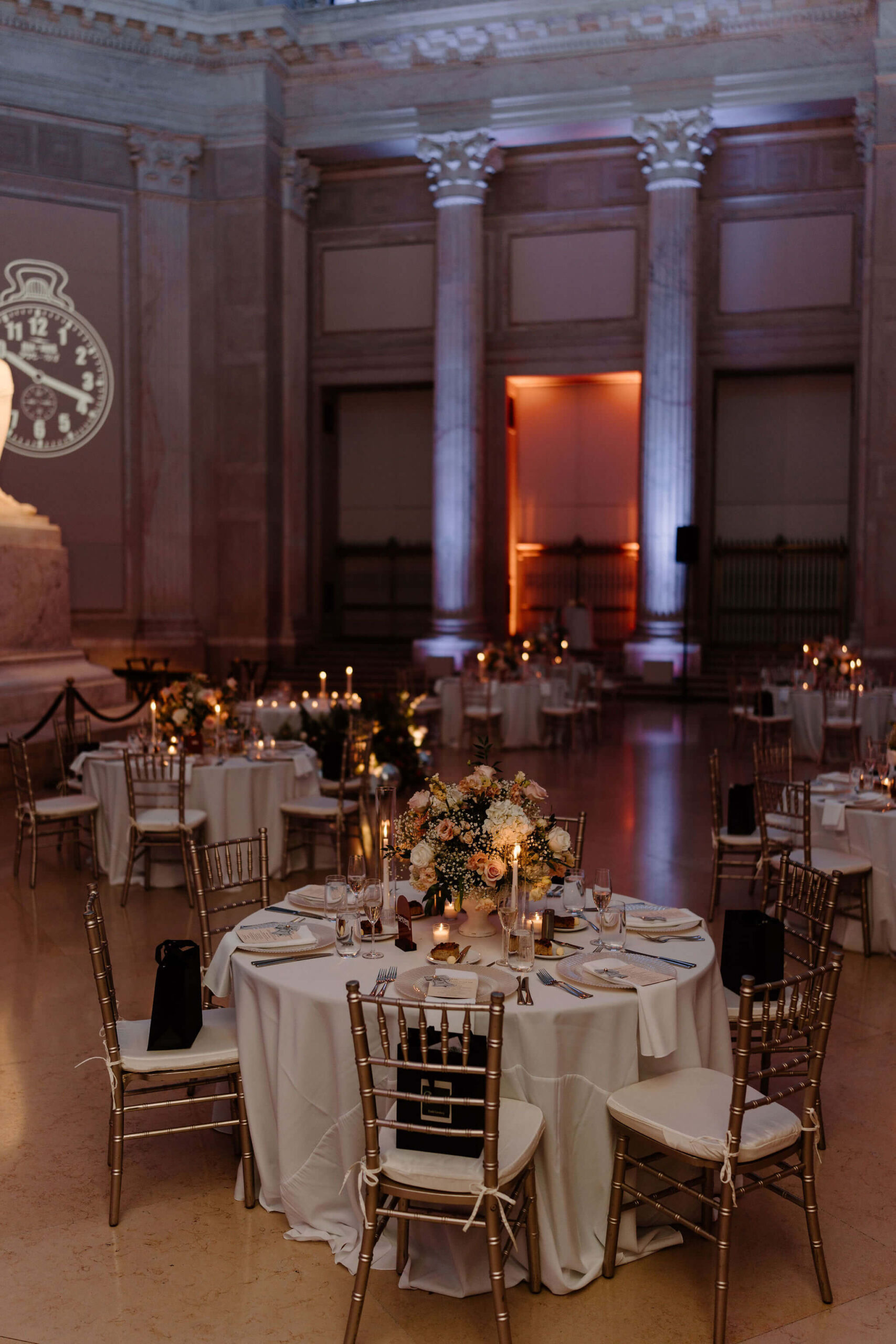 formal wedding reception space, each table decorated with white linens, a colorful floral centerpiece, and tall candlesticks