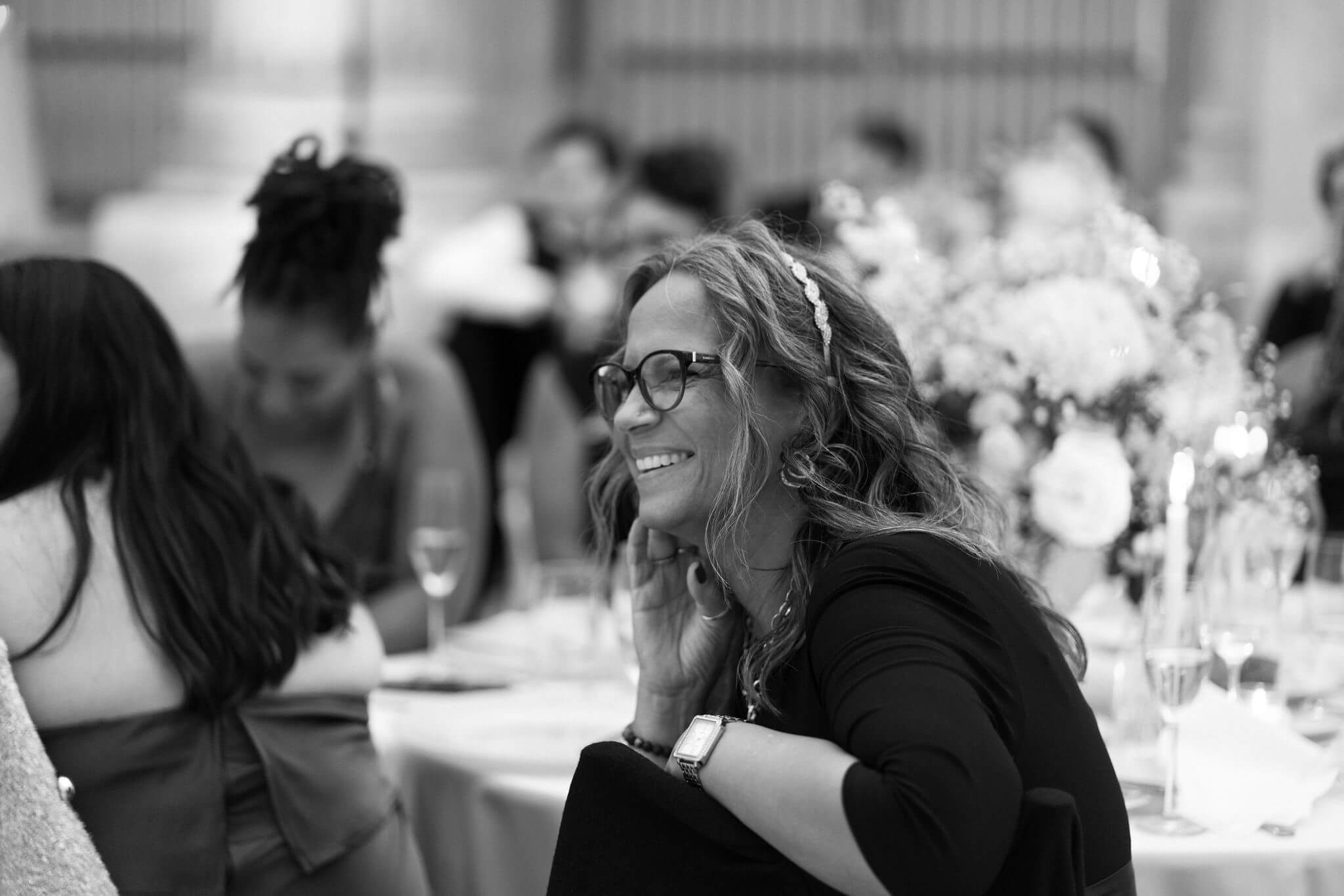 black and white image of a guest watching a first dance and smiling widely