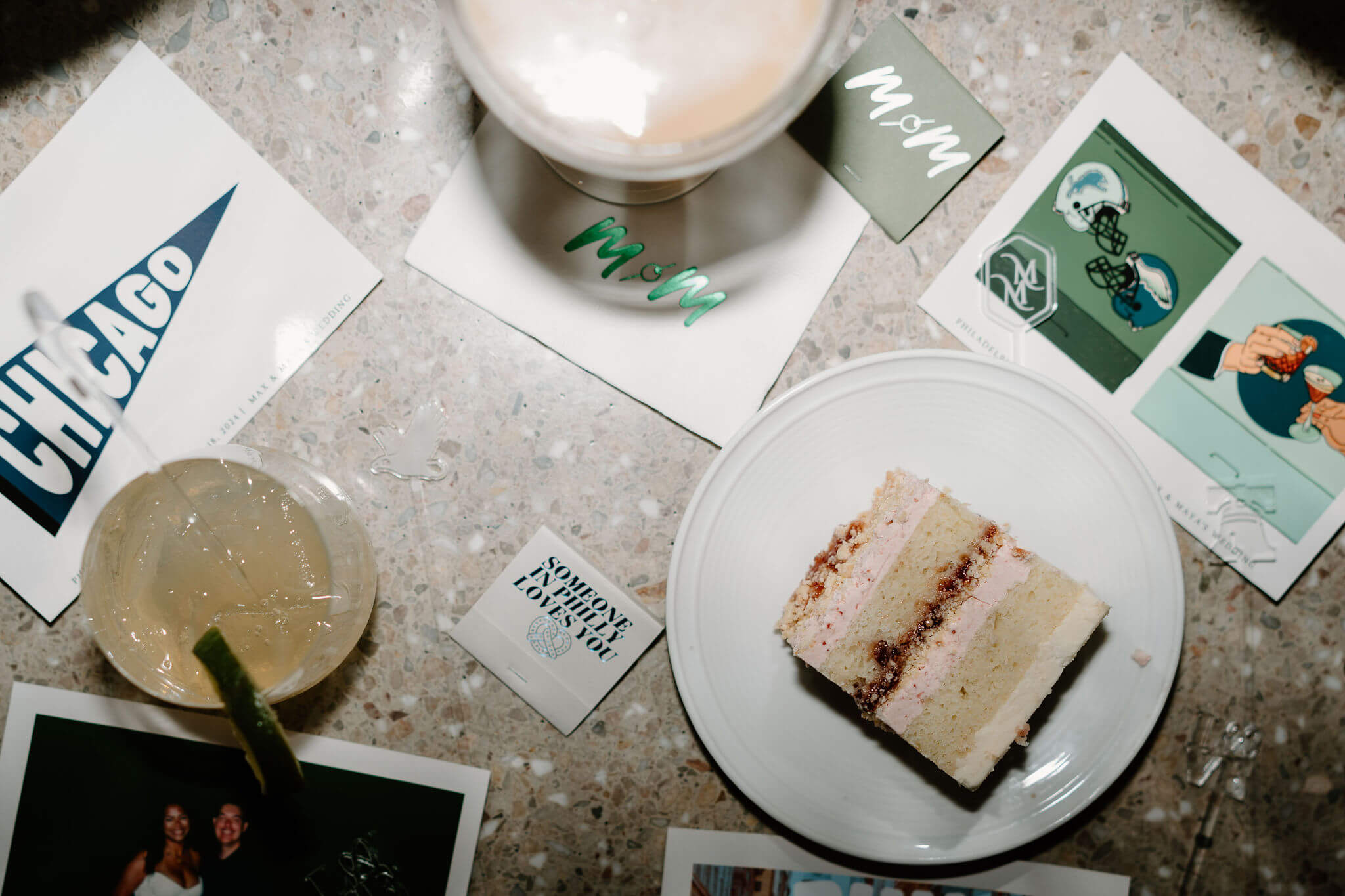 late-night flat lay at a wedding reception, featuring an espresso martini, a mule, a slice of wedding cake, post cards, a matchbox, and disco balls