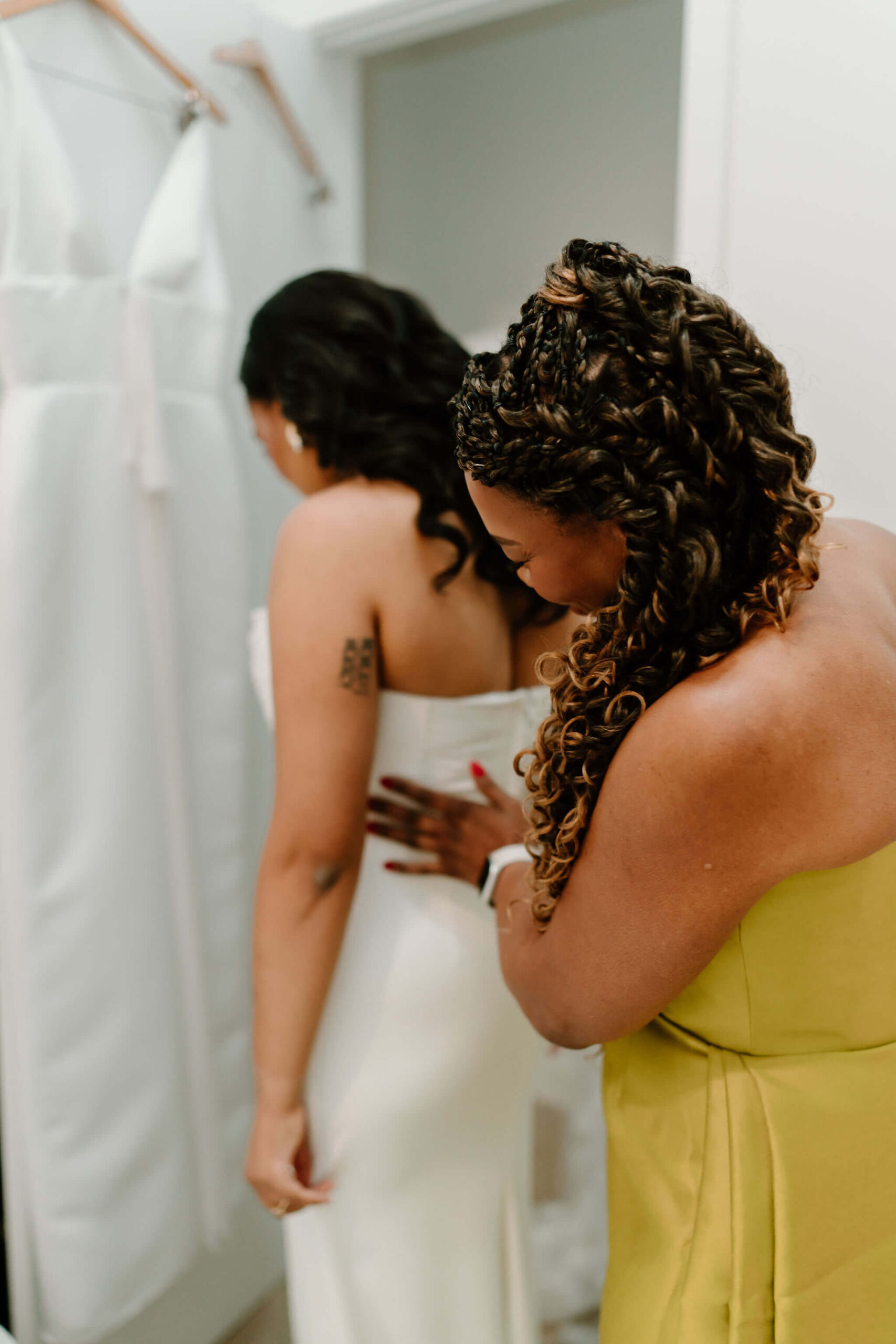 mother of the bride making sure the bride is securely in her wedding dress