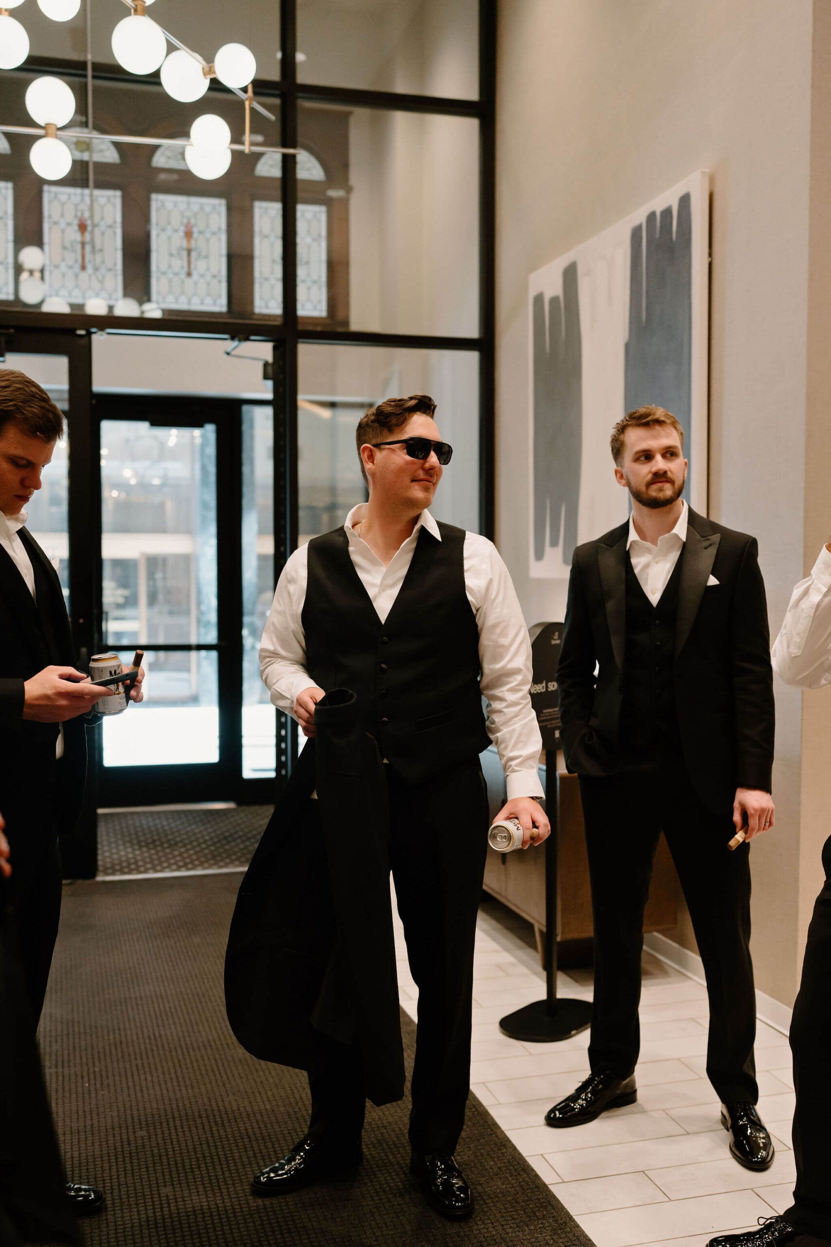 groom in black suit, holding his jacket in his hand, surrounded by other groomsmen in black suits