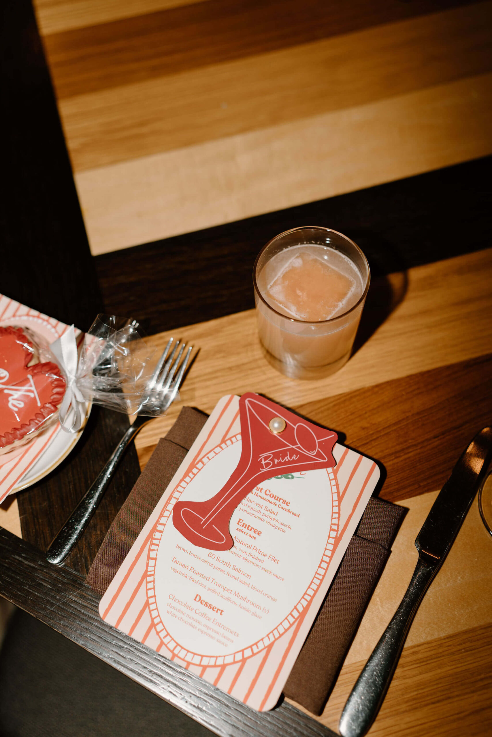 close up of a red and white menu and a martini-shaped seating place card at a rehearsal dinner, with a cocktail at the placemat