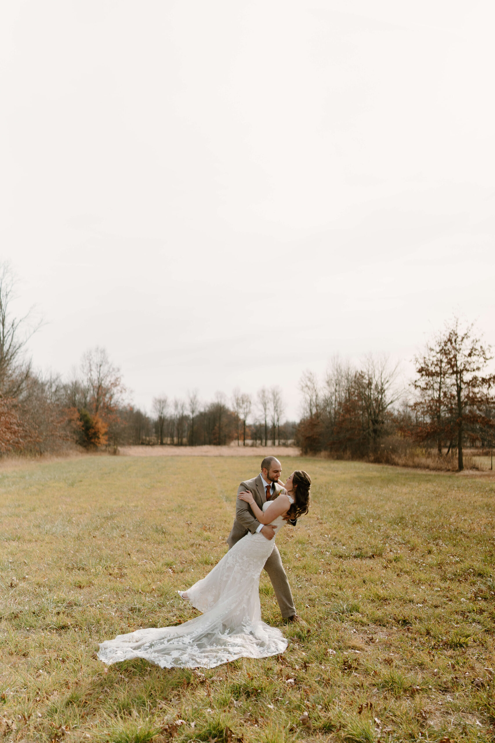 groom dipping bride in an open field on their wedding day