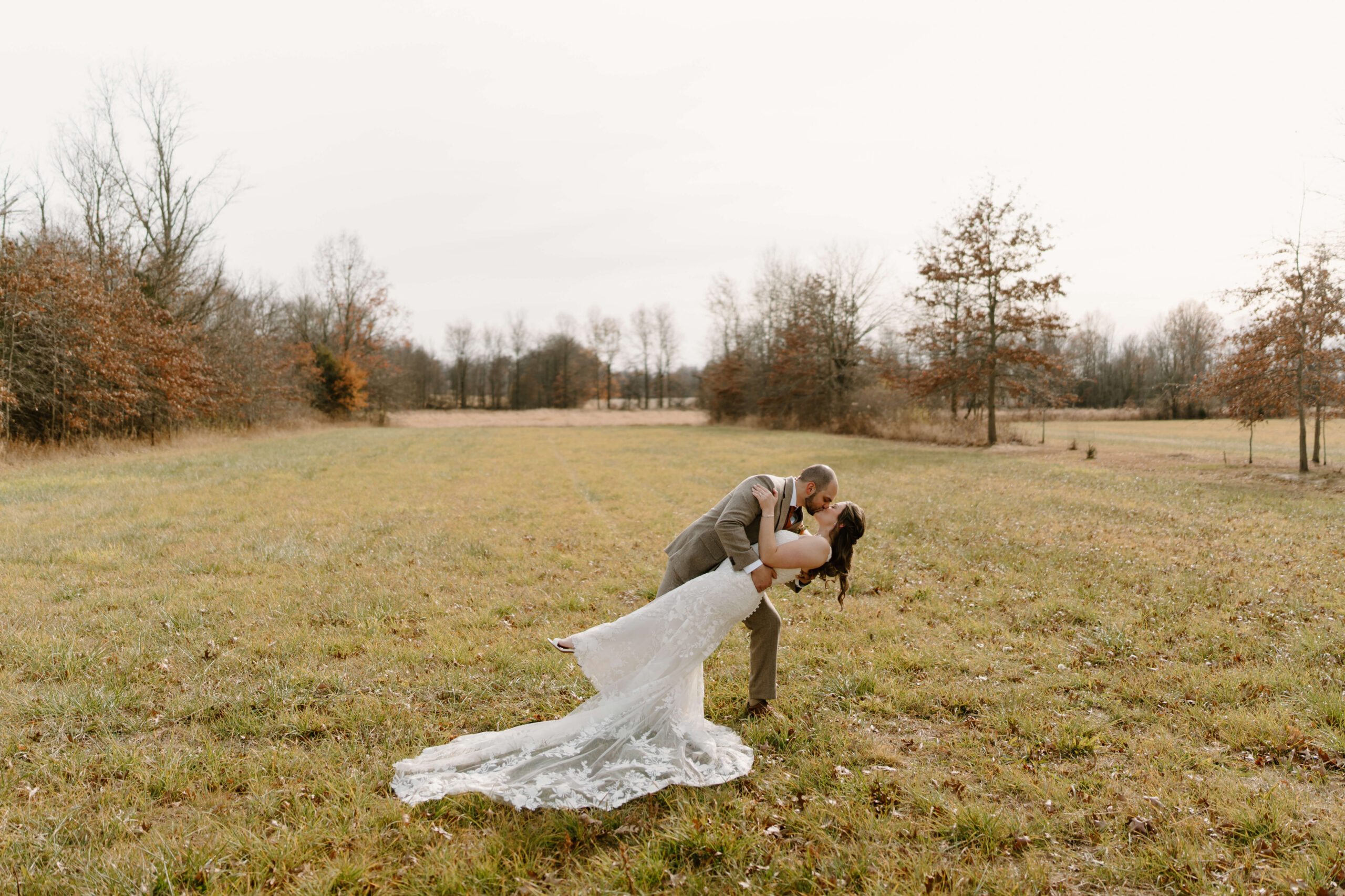 groom dipping bride in an open field on their wedding day
