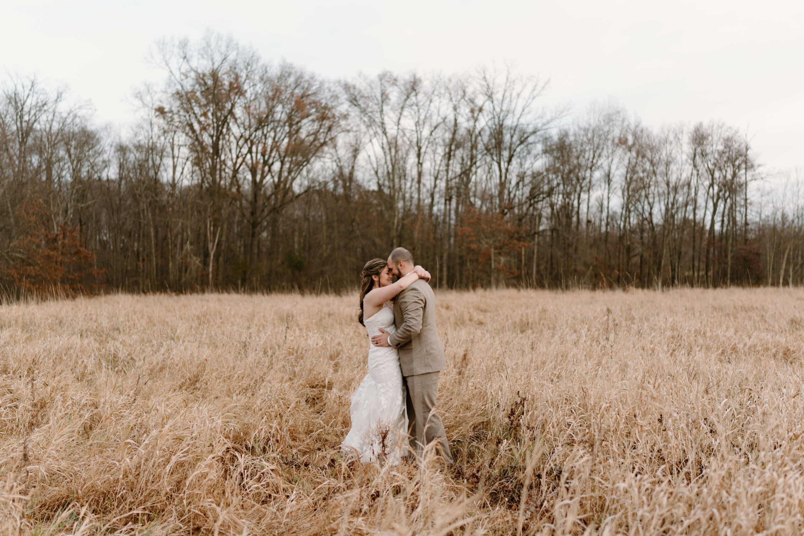 bride and groom embracing in a field during golden hour portraits after their November wedding at the Farm Bakery and Events in Pennsylvania
