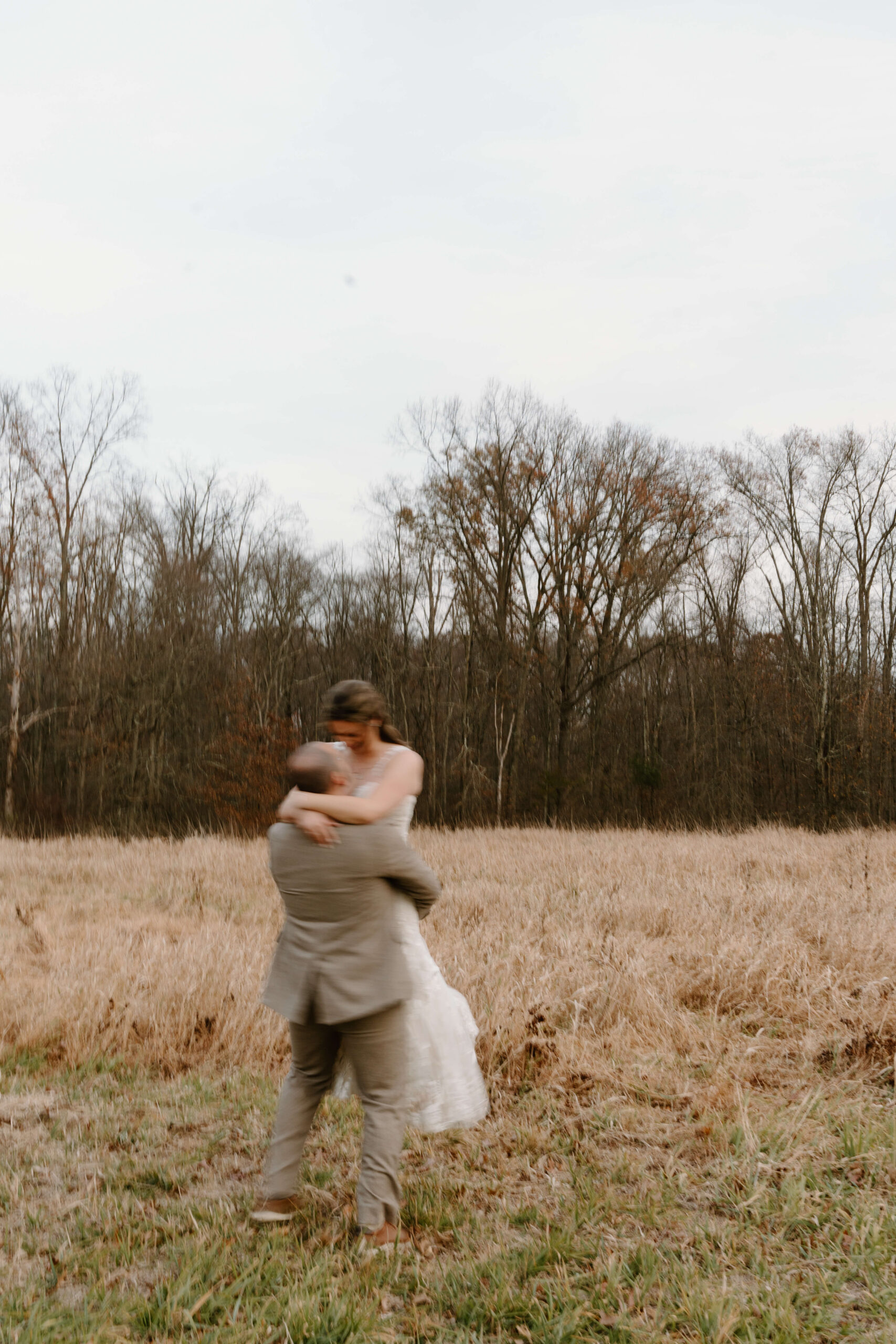 motion-blur image at sunset of groom lifting bride and spinning in a field after their November wedding day at the Farm Bakery and Events